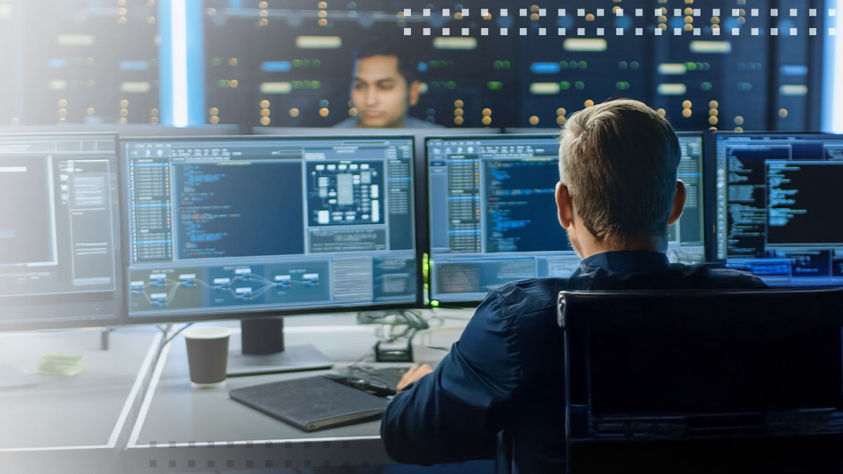 IT specialist works on personal computer with screens showing software program with coding language interface